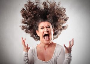 Middle-aged woman with bristling hair and screaming in despair